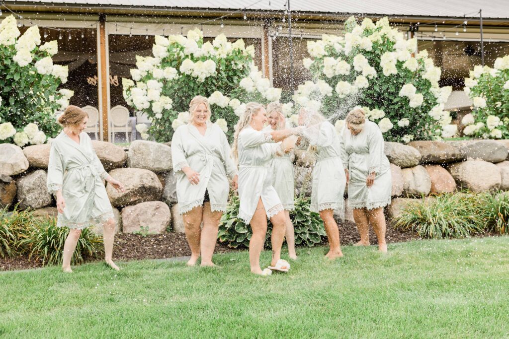Bride and bridesmaids popping champagne on her wedding day dressed in matching robes. 